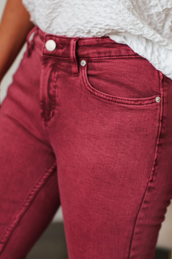 A closeup of the pocket and rise of ruby colored  jeans.