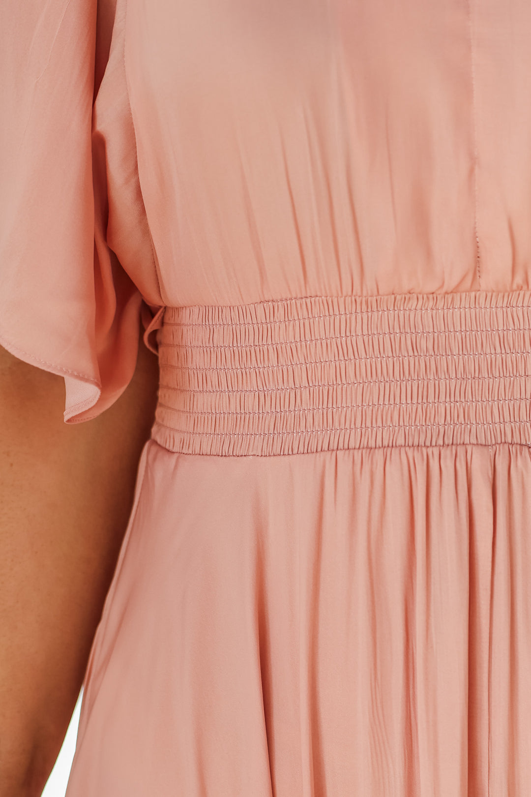 A closeup of the smocked waist on a peach colored dress.