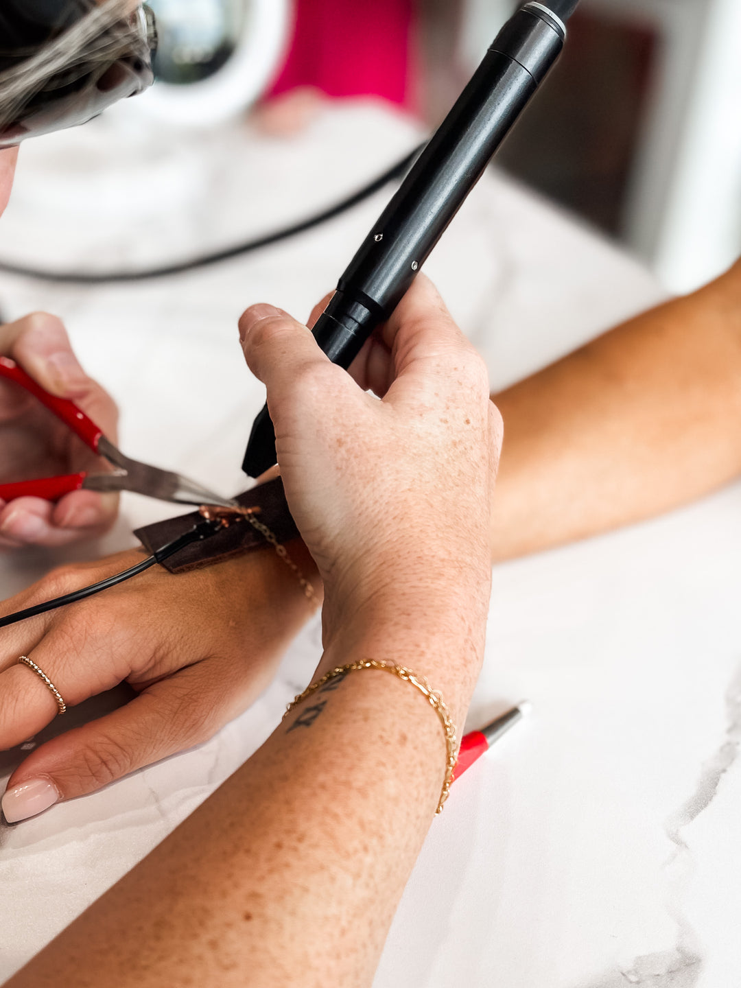 A close up photo of a girl using a micro welder to weld a permanent bracelet.