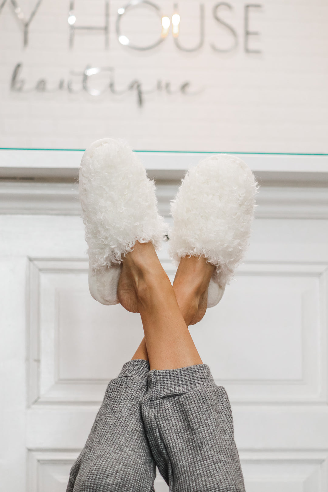 A photo of a woman wearing white furry slippers.