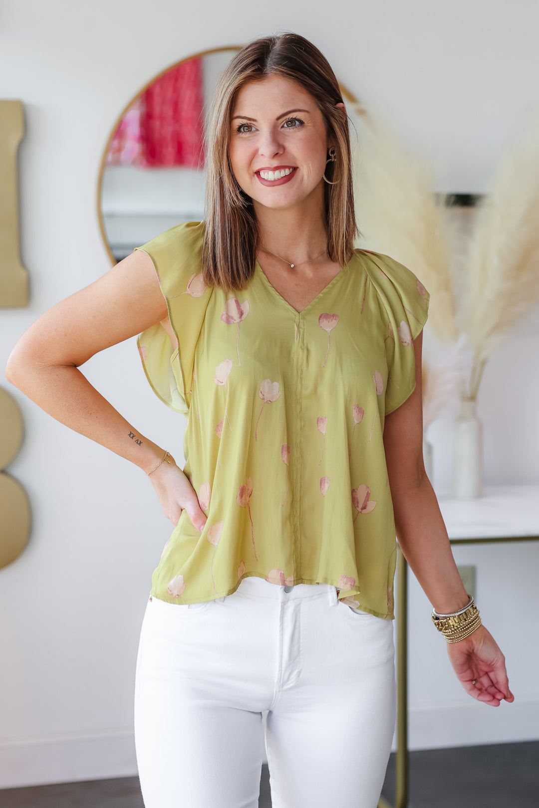 Image of brunette girl wearing a green top. The background is the front door of Ivy house Boutique 