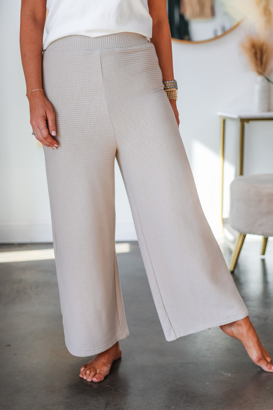 A closeup of a woman wearing wide leg rib pants in a cream color.