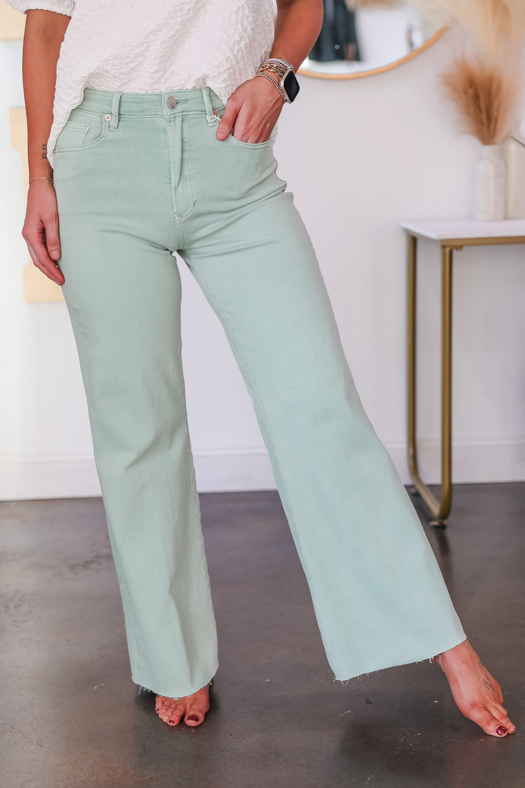 A woman wearing a pair of Dear John mint colored wide leg jeans.