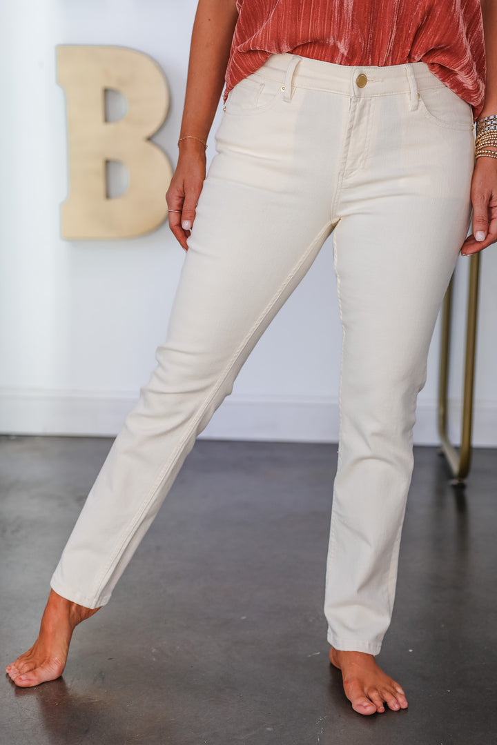 A woman standing in a shop wearing cream colored jeans.