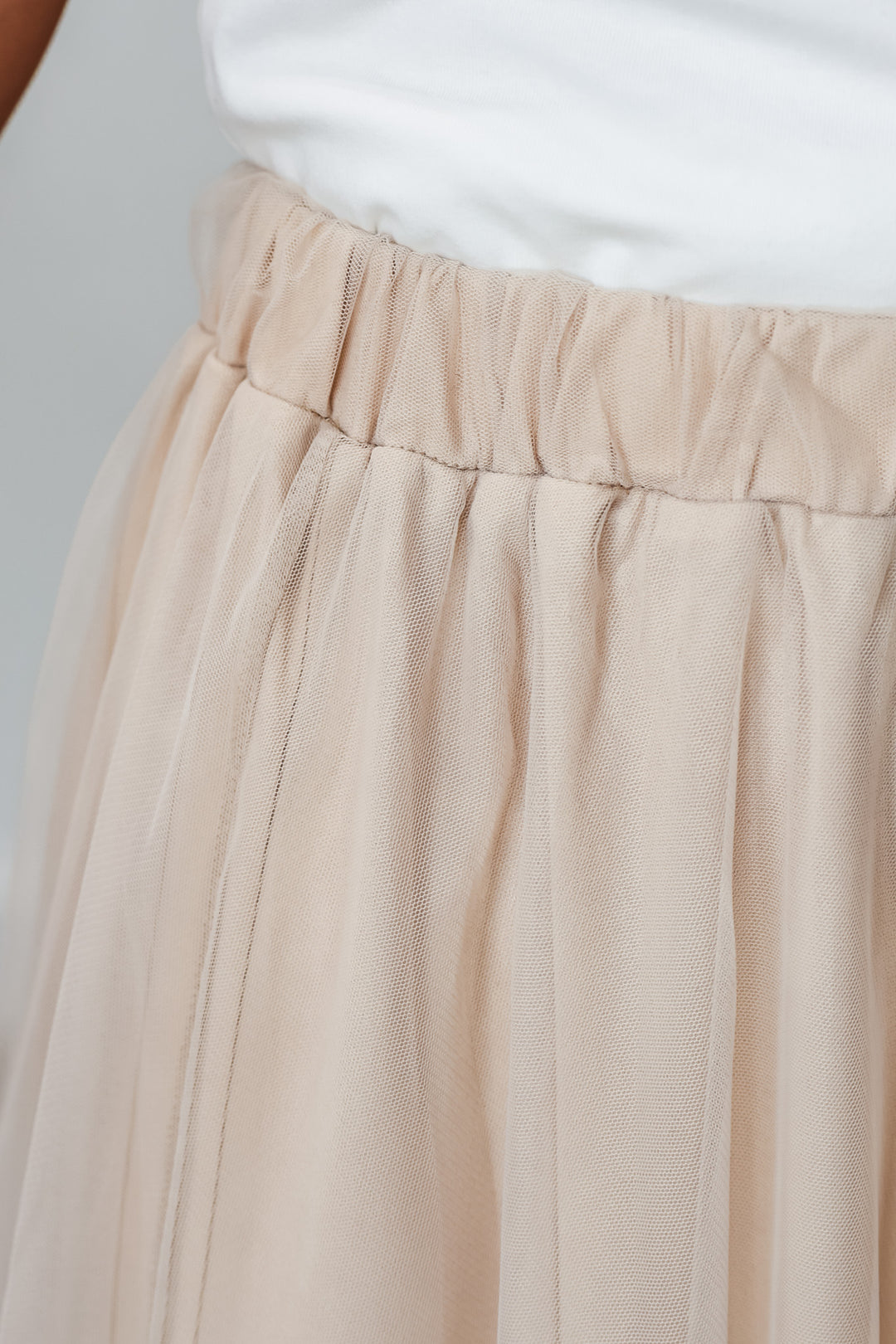 A closeup of a a woman wearing a champagne colored tulle skirt with an elastic waist.