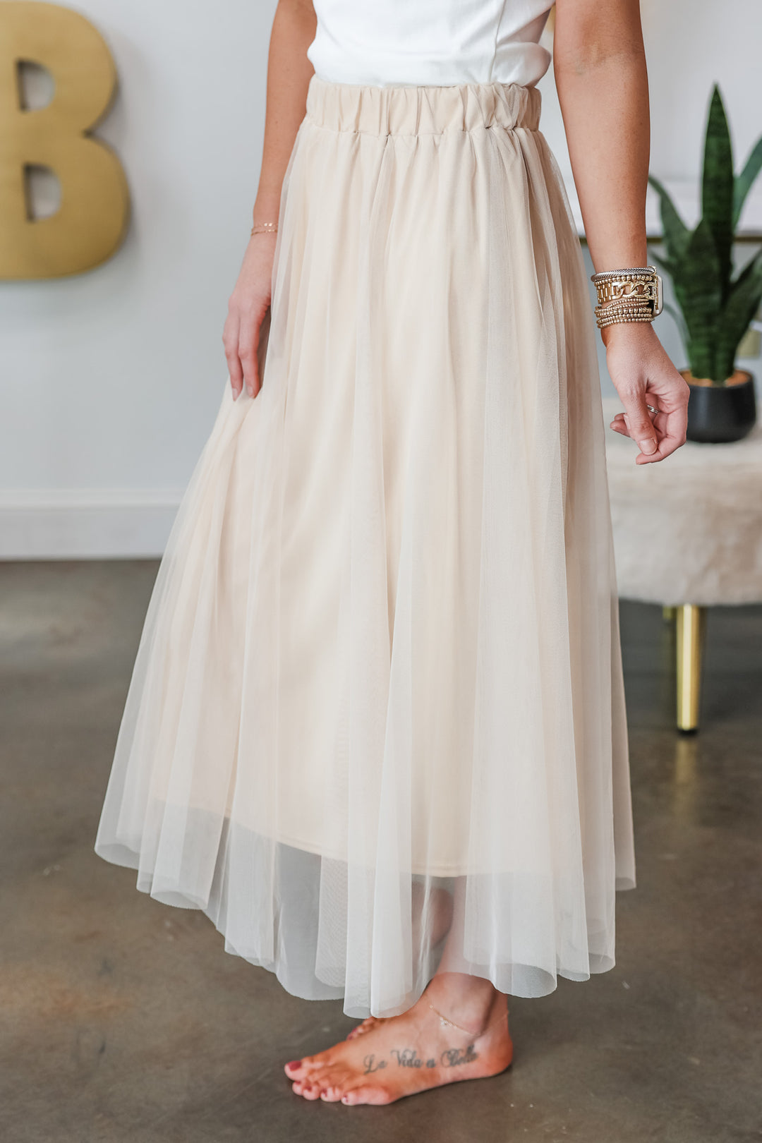 A picture of a woman standing in a shop wearing a champagne colored tulle skirt with an elastic waist