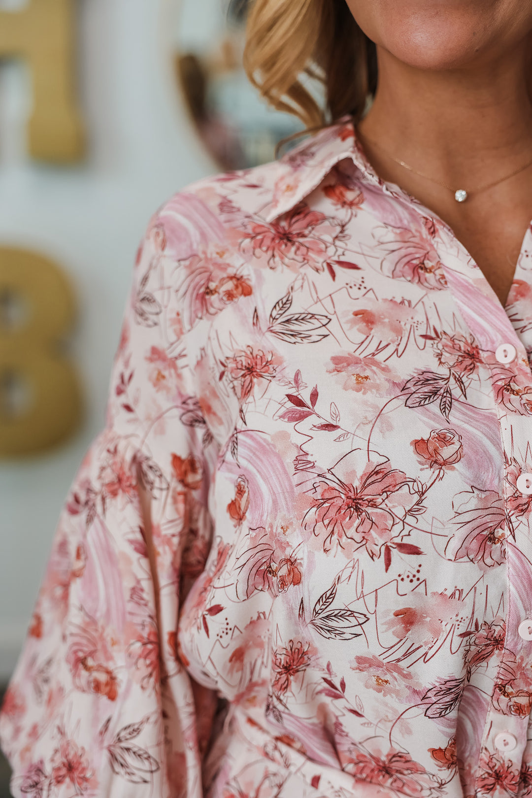 A closeup of the shoulder of a pink bubble sleeve floral print shirt dress with adjustable belt.