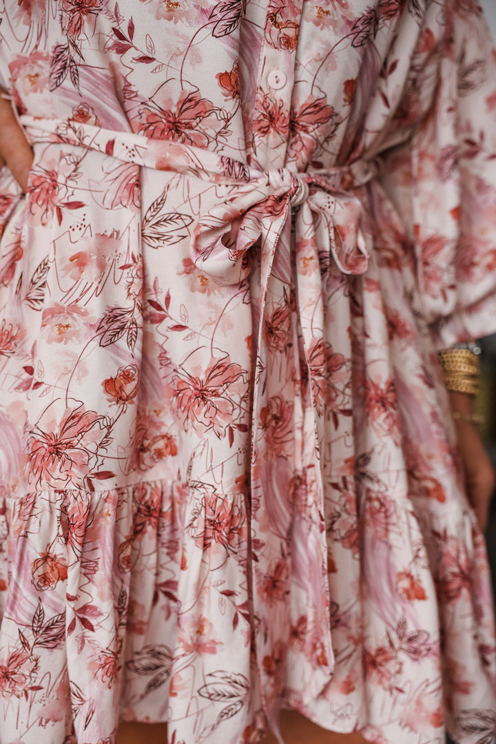 A closeup of the adjustable tie belt on a pink bubble sleeve floral dress.