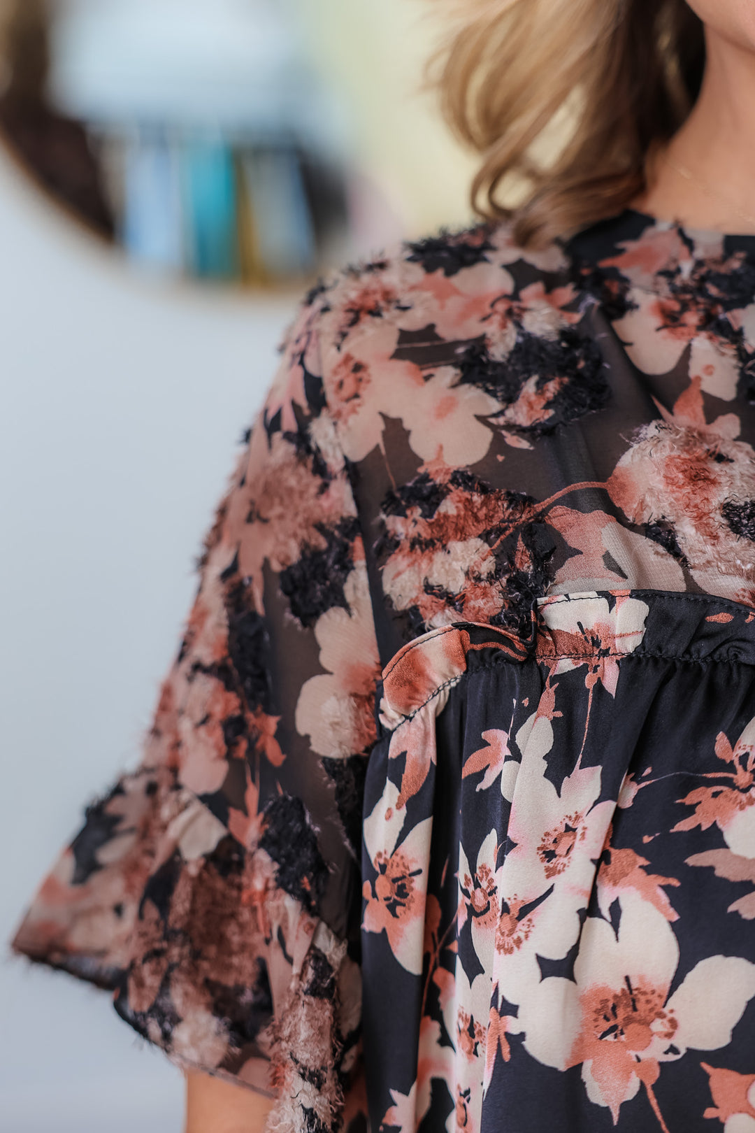 A closeup of the shoulder on a black and mauve floral print top.