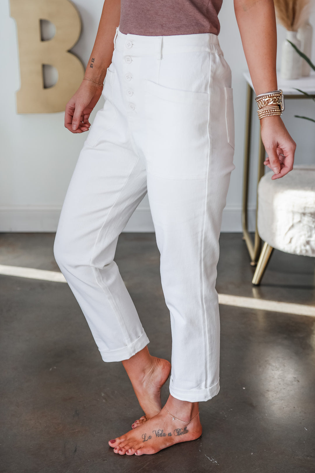 A closeup of a woman wearing white cotton twill pants with button front and pockets.