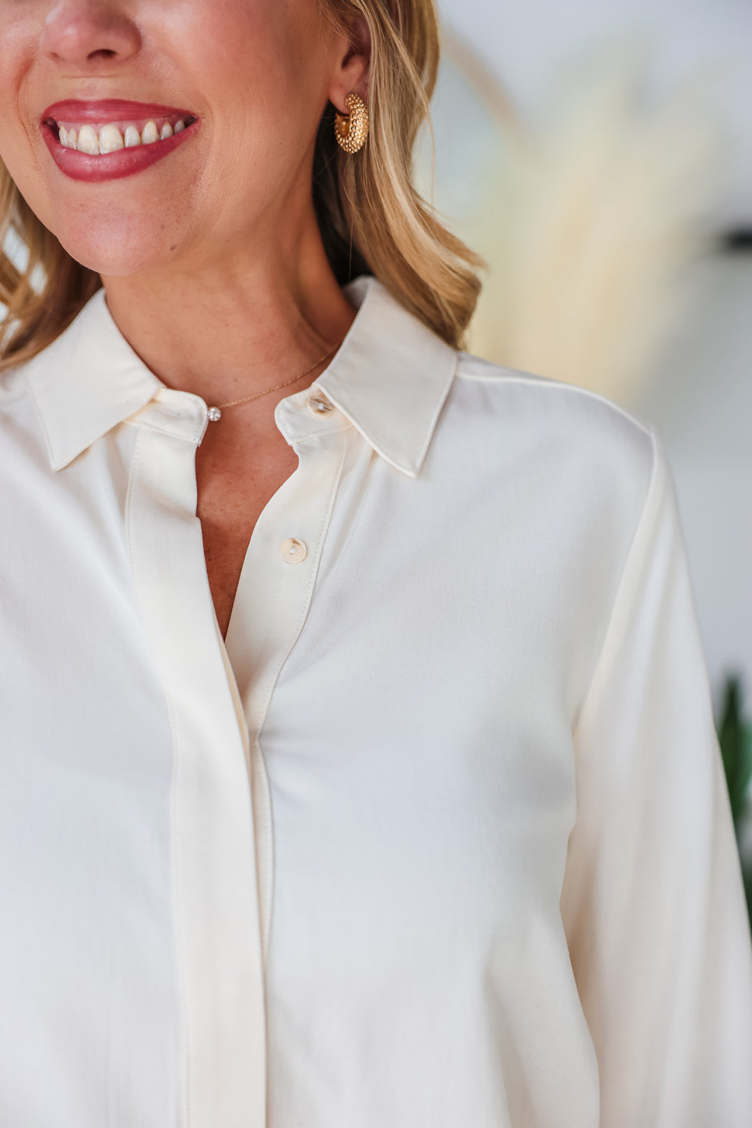A closeup of the shoulder of a woman wearing a cream colored button down.