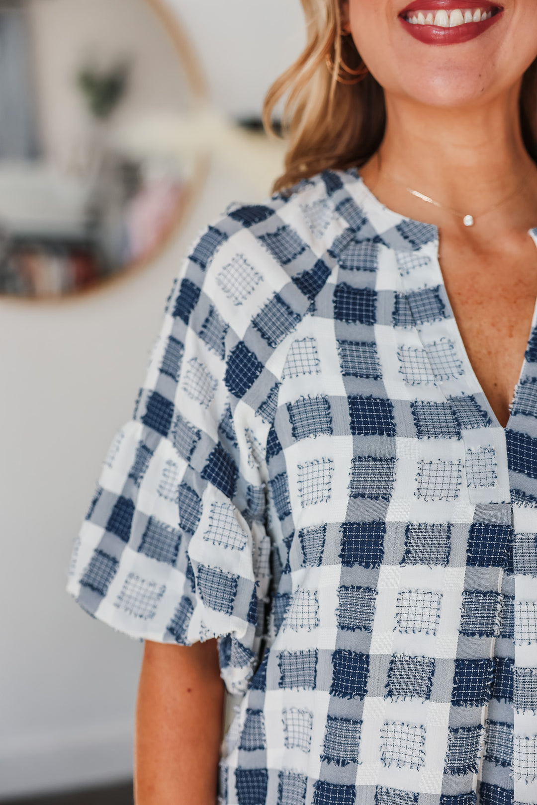 A closeup of the short balloon sleeve and v neck on a white and navy patchwork detail dress.