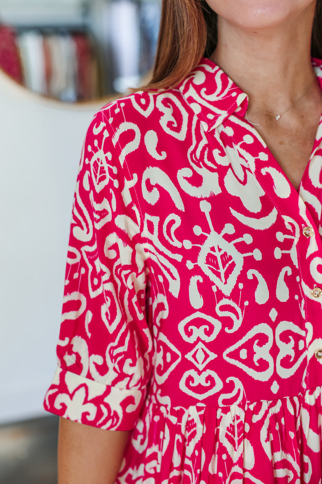 A closeup of the abstract print on a fuchsia and cream colored dress with button collar and 3/4 length sleeves.