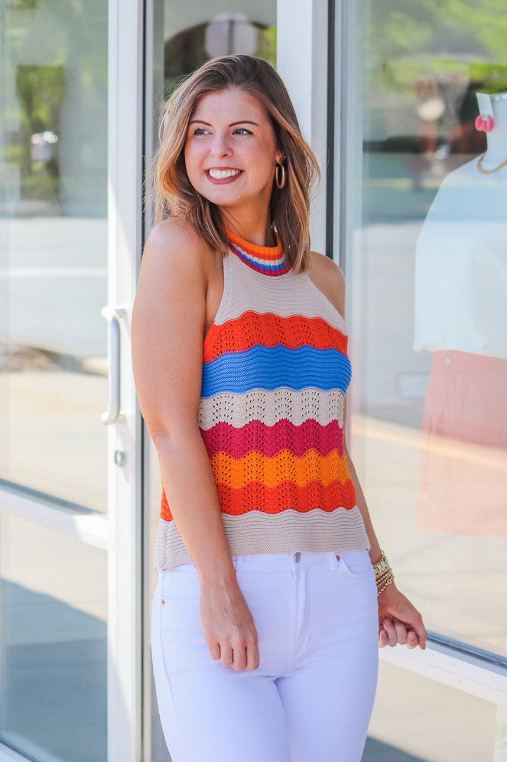 Brunette girl wearing a striped crochet halter top standing in front of a store.