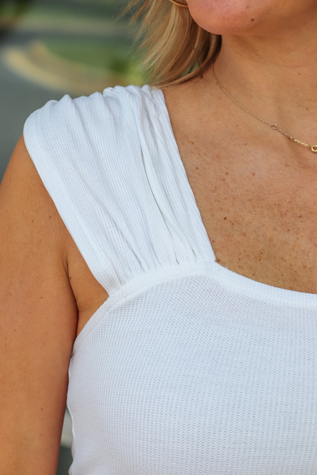 A closeup of the gathered shoulder on the white top with a square neckline.