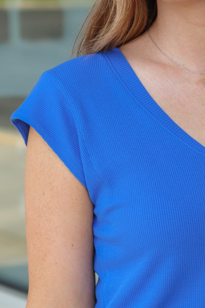 A close up of a woman's shoulder wearing a blue shirt.