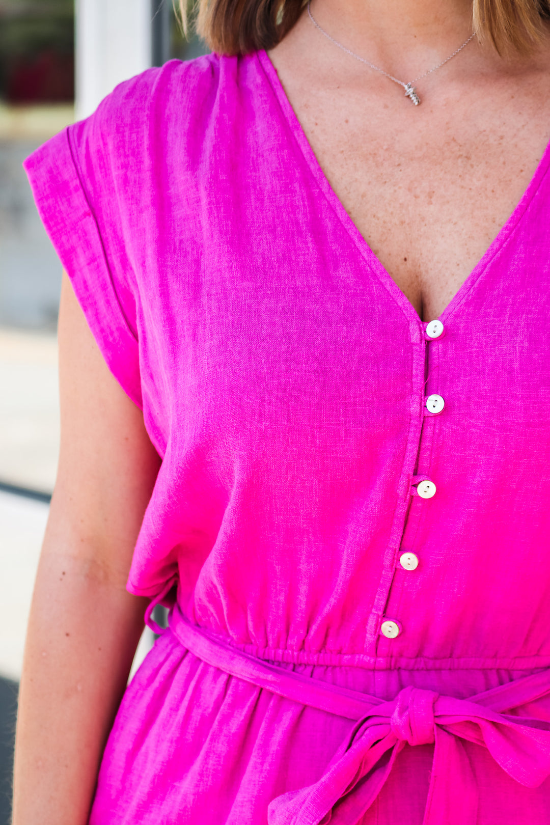 Girl wearing a hot pink romper with button closure on top and elastic waist.