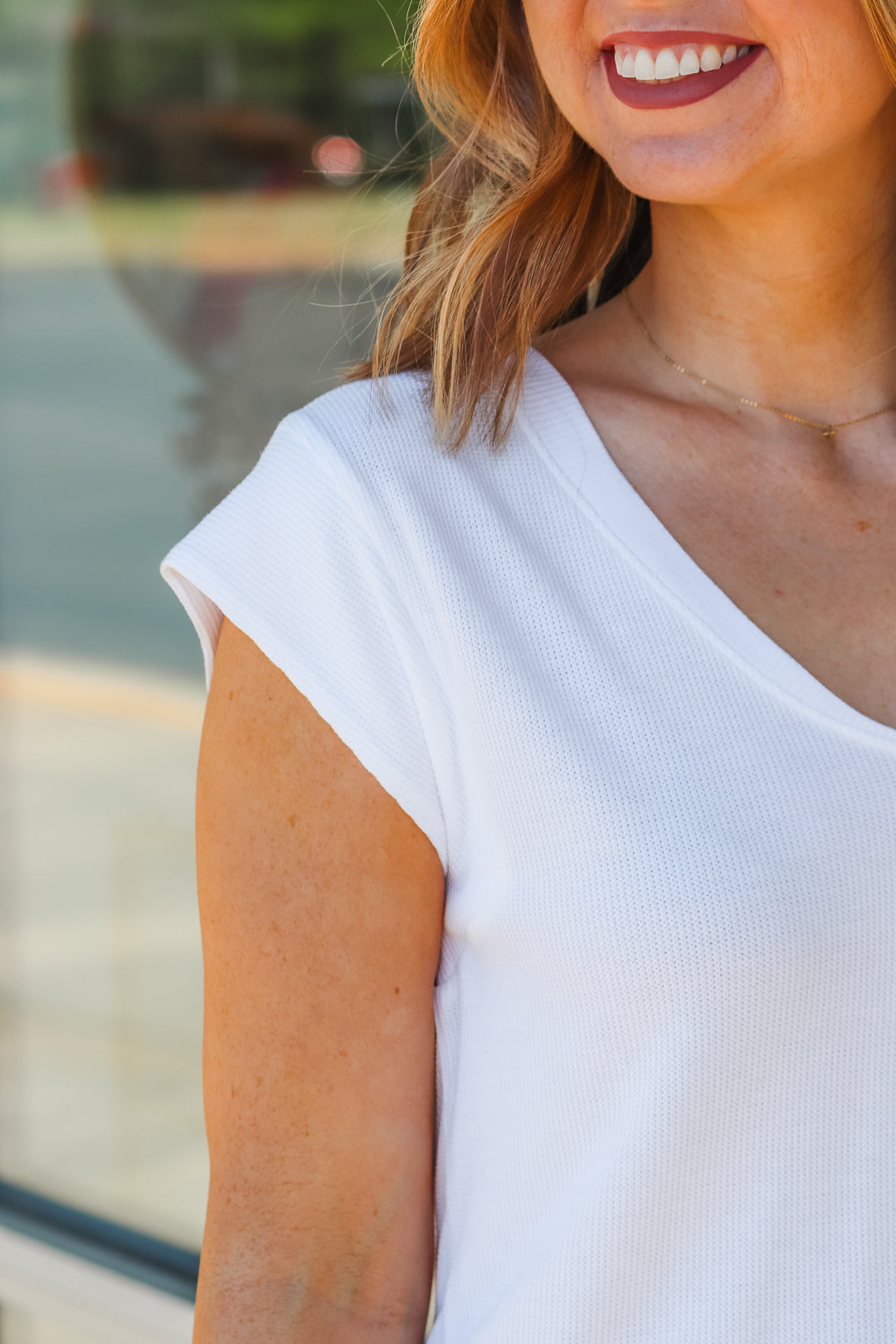 A close up of a woman's shoulder wearing a white shirt.