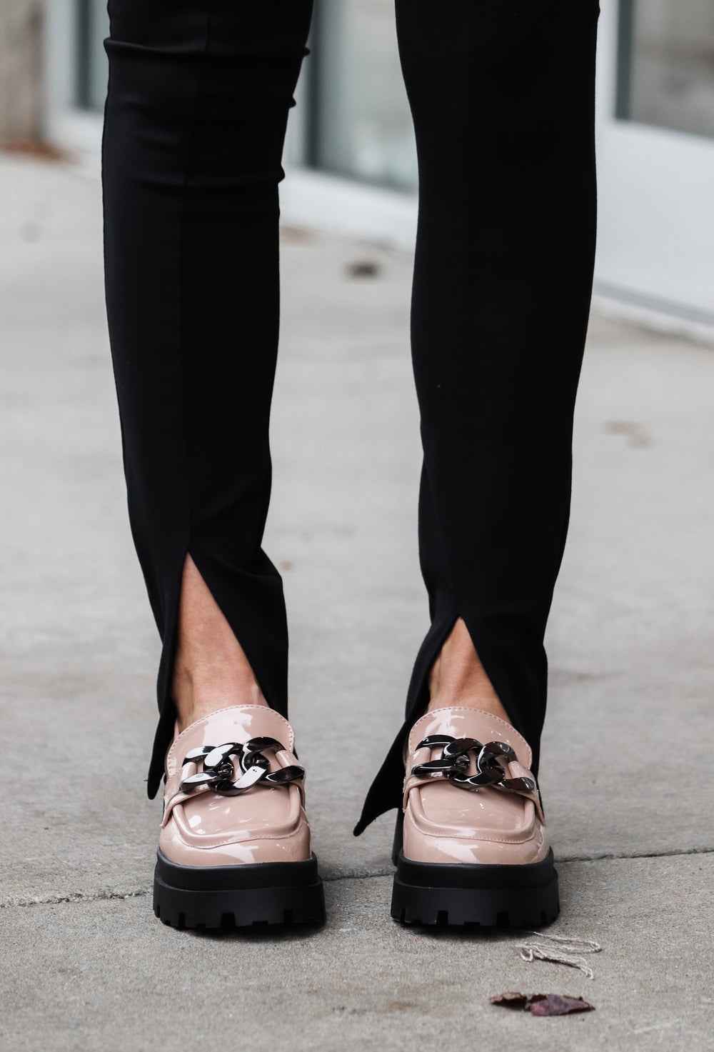 A closeup of the ankles of a woman wearing black front slit hem leggings.